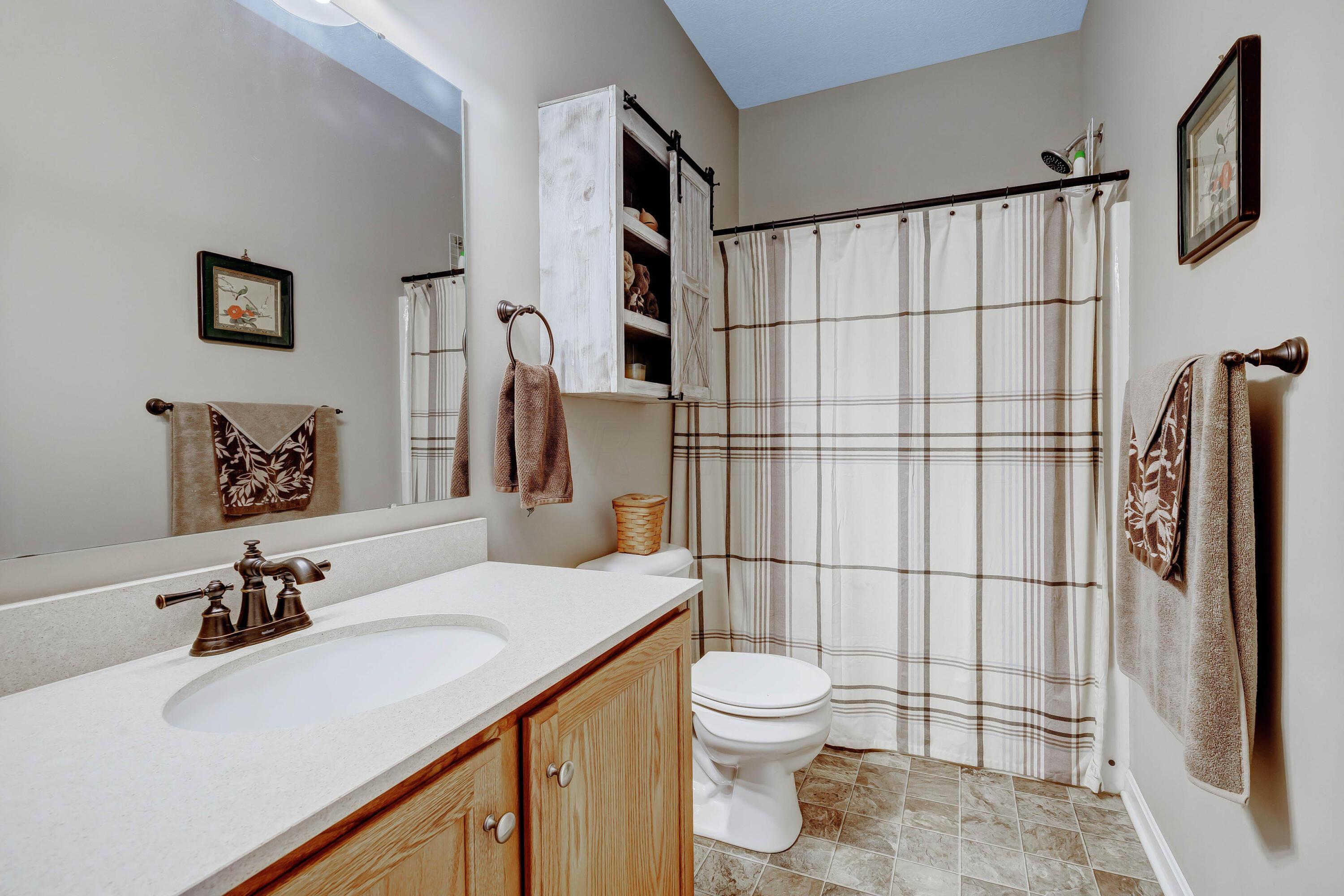 16347 Murphy Road Sunbury, OH 43074 - Photo 32 of 74 • Neutral vinyl flooring • Tan painted walls • Tub/shower combination • Ceiling exhaust • Enclosed vanity with single bowll, cultured marble sinktop • Wall cabinet • 3 bulb wall light
