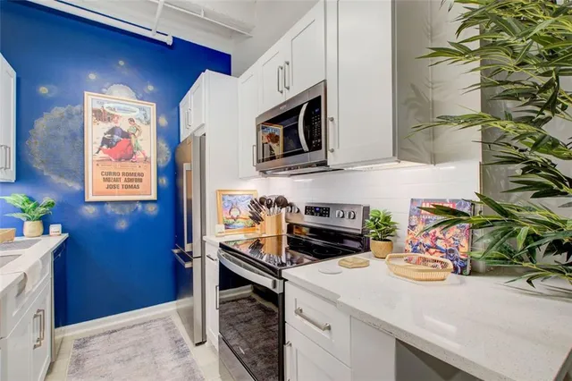 a kitchen with stainless steel appliances a sink a stove and white cabinets