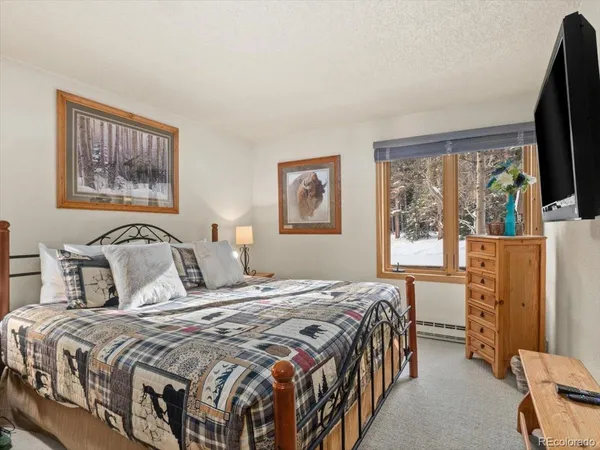 a bedroom with a bed a dresser next to a window