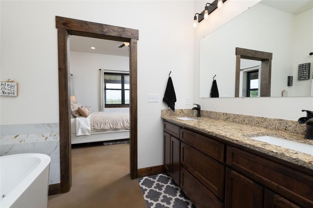 5543 Gray Road Nocona, TX 76255 - Photo 18 of 36 a en suite bathroom with a granite countertop sink and a mirror