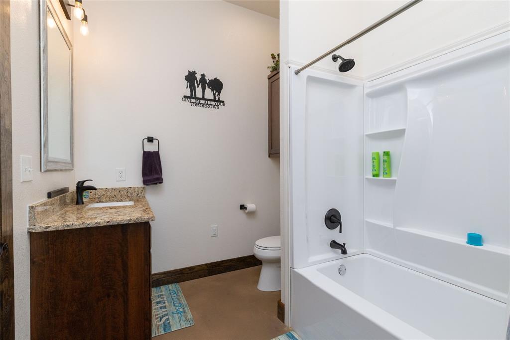 5543 Gray Road Nocona, TX 76255 - Photo 20 of 36 a bathroom with a granite countertop sink a toilet and shower