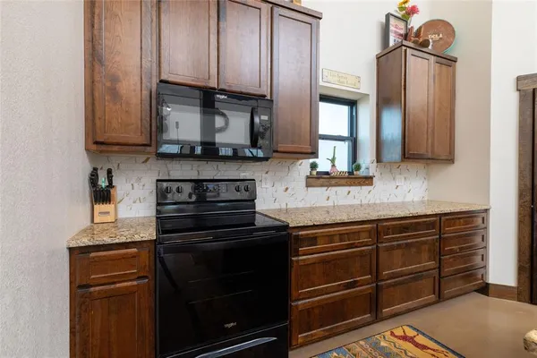 a kitchen with granite countertop wooden cabinets and a stove top oven