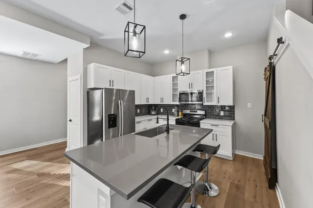 a kitchen with stainless steel appliances granite countertop a refrigerator a sink dishwasher a stove and a refrigerator with wooden floor