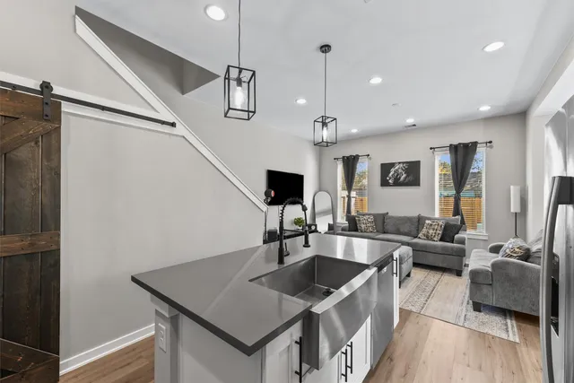 a kitchen with stainless steel appliances granite countertop a sink dishwasher a dining table and chairs with wooden floor