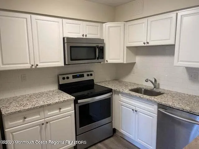 a kitchen with granite countertop cabinets stainless steel appliances and a sink