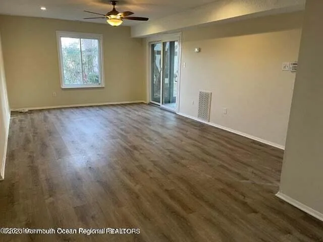 a view of an empty room with a window and wooden floor