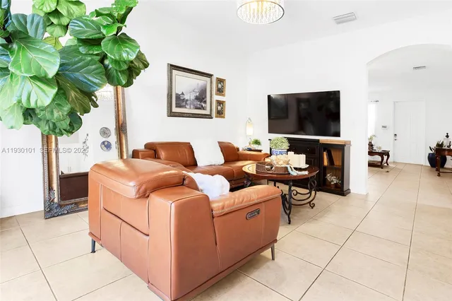 a living room with furniture flowerpot and a flat screen tv