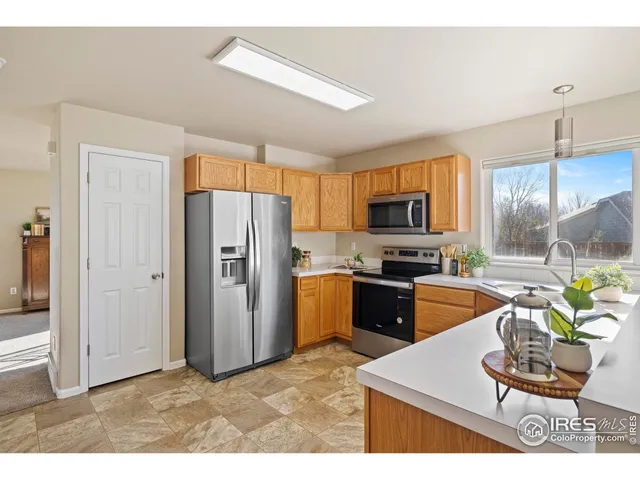 a kitchen with stainless steel appliances granite countertop a refrigerator a stove top oven a sink dishwasher and wooden cabinets with large window