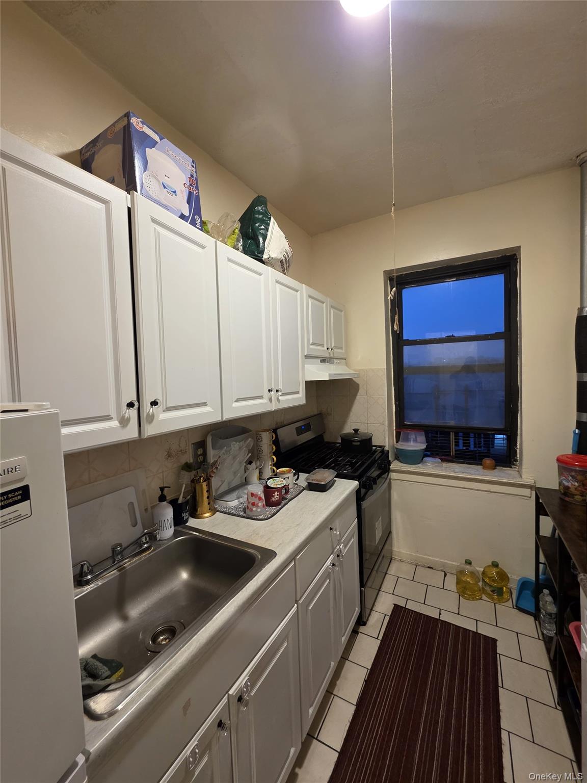 70-35 Broadway, Unit D10 Queens, NY 11372 - Photo 4 of 6 a kitchen with a sink stove top oven and cabinets