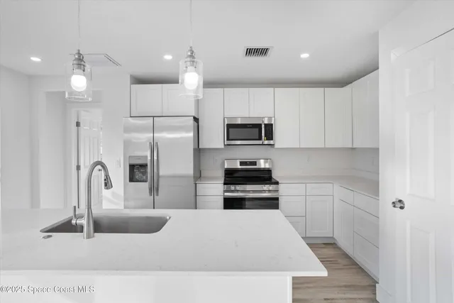 a kitchen with kitchen island a sink stainless steel appliances and cabinets