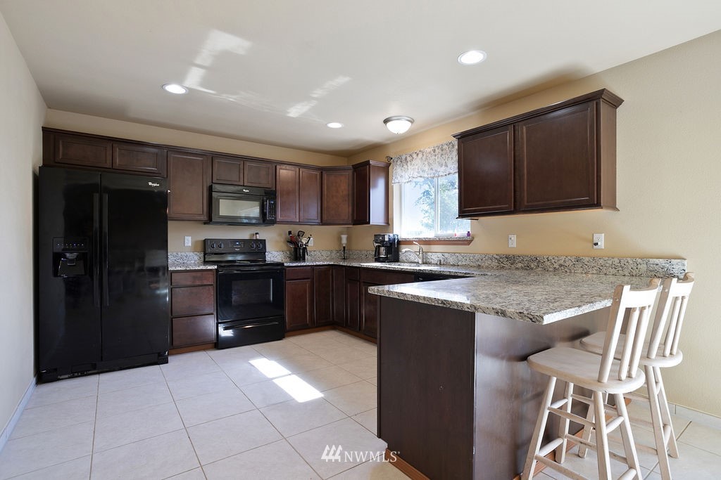 6307 192nd Lane Southwest Rochester, WA 98579 - Photo 10 of 25 a kitchen with granite countertop a refrigerator and a stove top oven