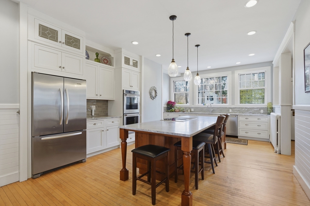372 Main Street Amesbury, MA 01913 - Photo 13 of 42 a kitchen with stainless steel appliances kitchen island granite countertop a refrigerator a stove a sink a dining table and chairs with wooden floor