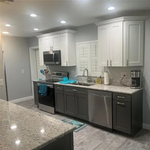 a kitchen with stainless steel appliances granite countertop a stove a sink and a microwave