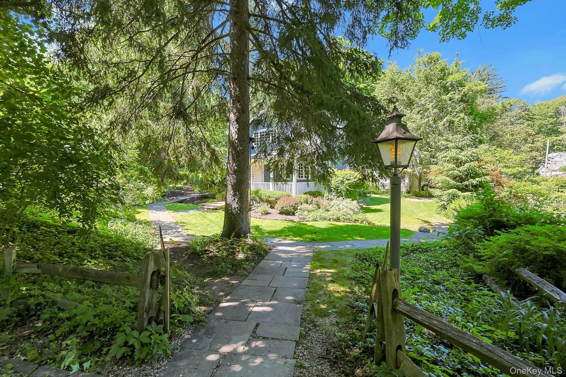 65 Douglas Road Chappaqua, NY 10514 - Photo 34 of 41 A charming walkway leads to the front of the home, surrounded by the beauty of the property’s landscaped grounds.