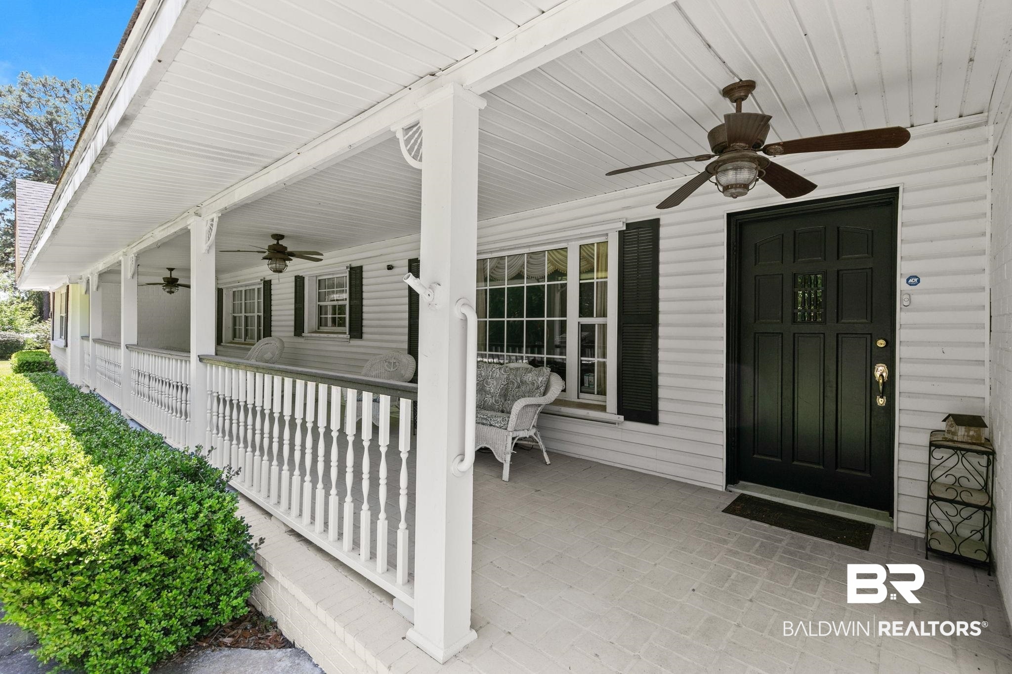 927 Cleveland Road Saraland, AL 36571 - Photo 2 of 80 Expansive covered porch featuring a white balustrade, ceiling fans, a dark paneled entry door with sidelights, and white siding