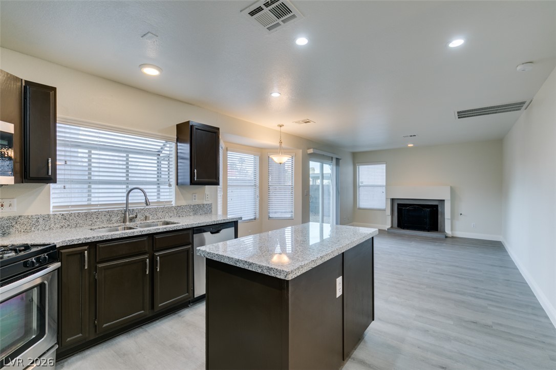 1738 Toltec Circle Henderson, NV 89014 - Photo 37 of 46 A contemporary kitchen seamlessly flows into a well-lit living area, highlighted by a cozy fireplace.