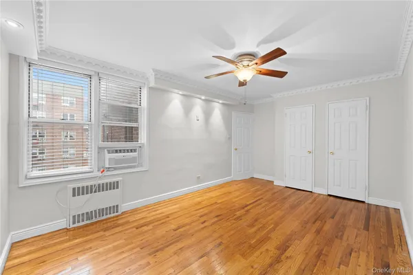 a view of empty room with wooden floor and fan
