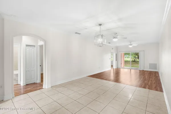 an empty room with chandelier fan and windows