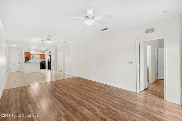 a view of a room with wooden floor and a ceiling fan