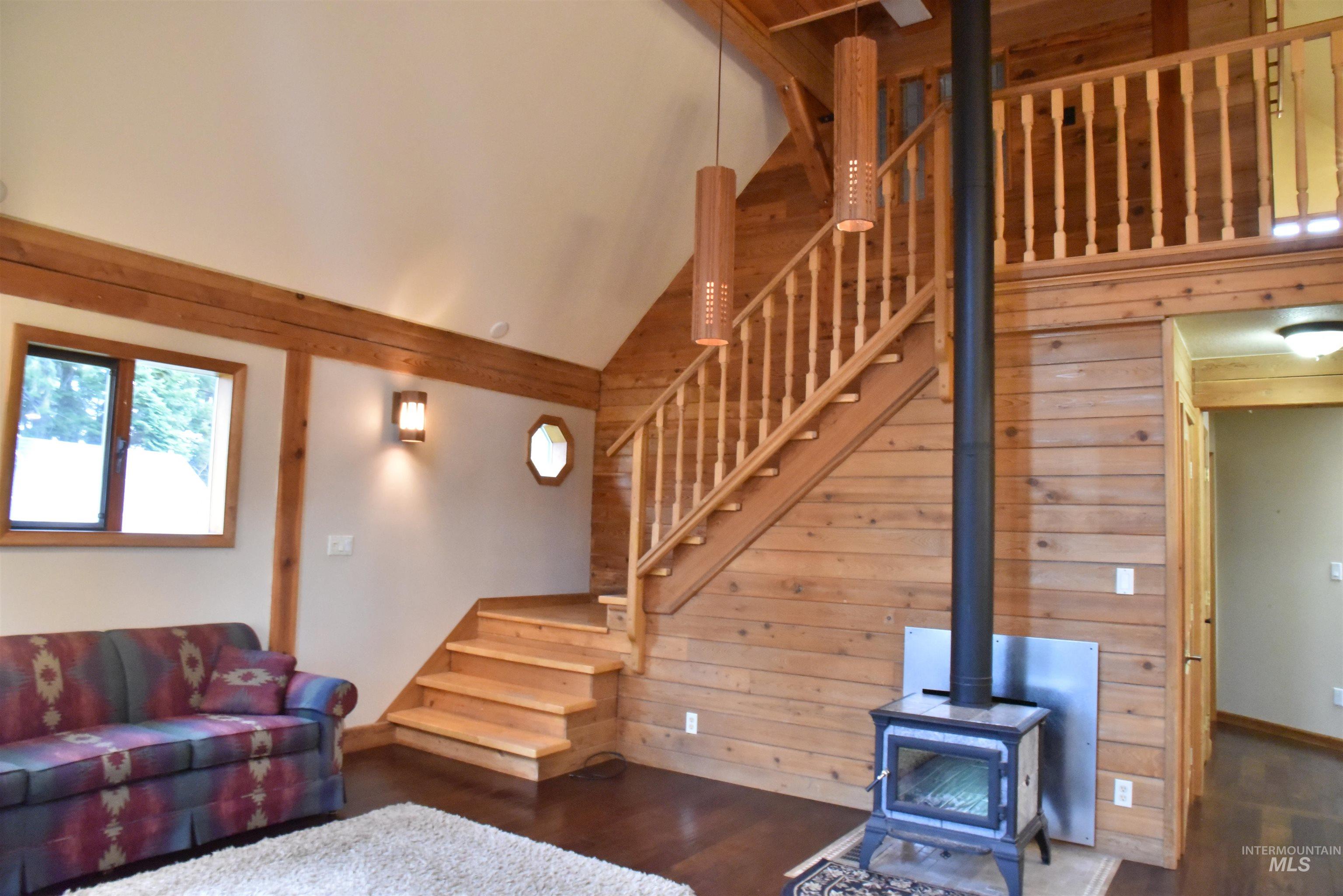 391457 Highway 95 Plummer, ID 83851 - Photo 8 of 39 Living area featuring a wood stove, wood finished floors, stairway, wood walls, and high vaulted ceiling