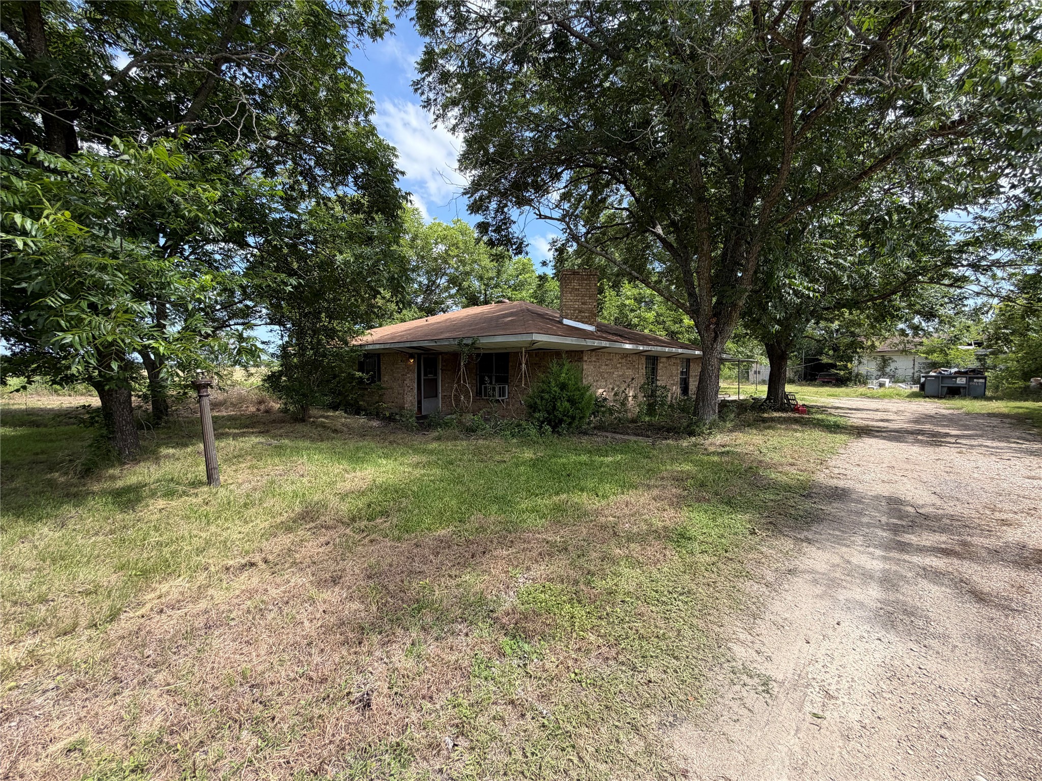 Mature trees shade this single-story brick residence with a charming front porch.