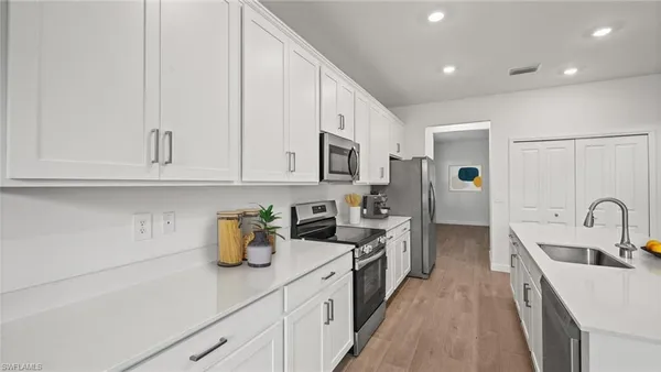 a kitchen with a sink dishwasher stove and white cabinets with wooden floor