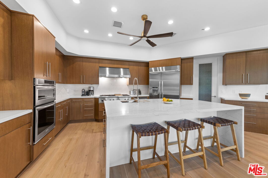 79400 Stonegate La Quinta, CA 92253 - Photo 12 of 46 a kitchen with granite countertop a stove top oven a sink dishwasher a dining table and chairs with wooden floor