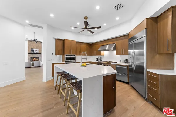 a kitchen with stainless steel appliances kitchen island a large counter top space a sink and a refrigerator