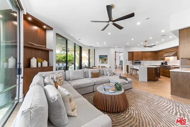 a living room with furniture kitchen view and a large window