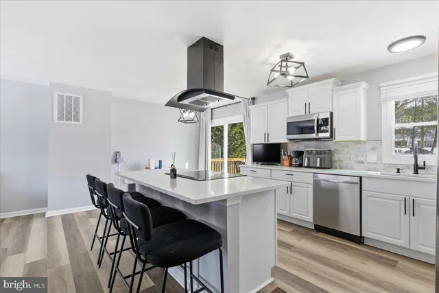 a kitchen with stainless steel appliances kitchen island granite countertop a table chairs sink and cabinets