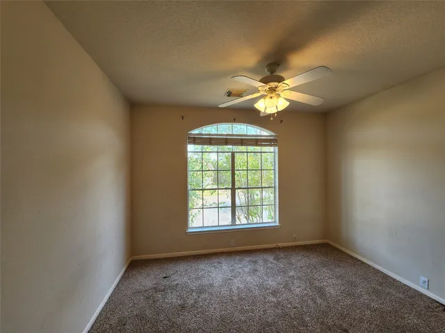 an empty room with a chandelier fan and windows