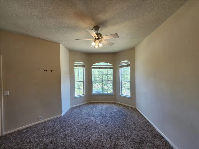 a view of a big room with windows and chandelier fan