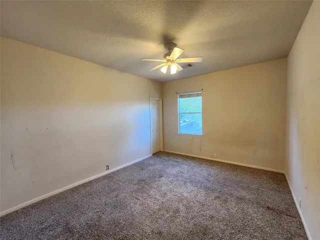 an empty room with a window and a fan