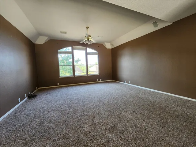 en empty room with windows and chandelier fan