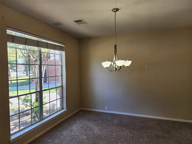 a view of a chandelier in big room with windows and chandelier