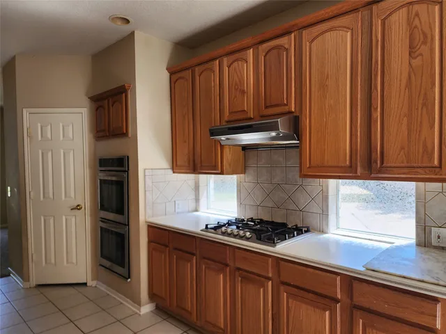 a kitchen with granite countertop cabinets and steel stove top oven