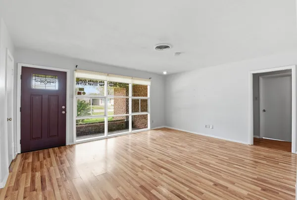a view of an empty room with wooden floor and a window