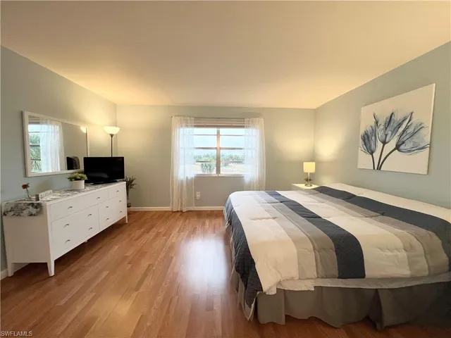 a spacious bedroom with a bed and a flat screen tv