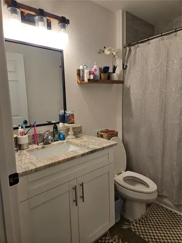 a bathroom with a granite countertop sink a toilet and a mirror