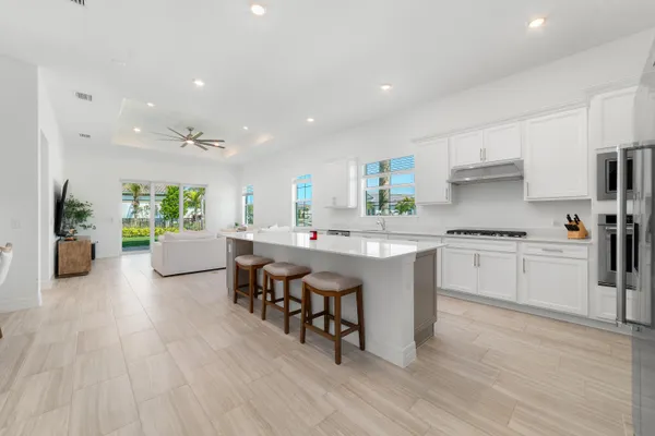 a kitchen with stainless steel appliances granite countertop a stove a sink a microwave a refrigerator and white cabinets with wooden floor