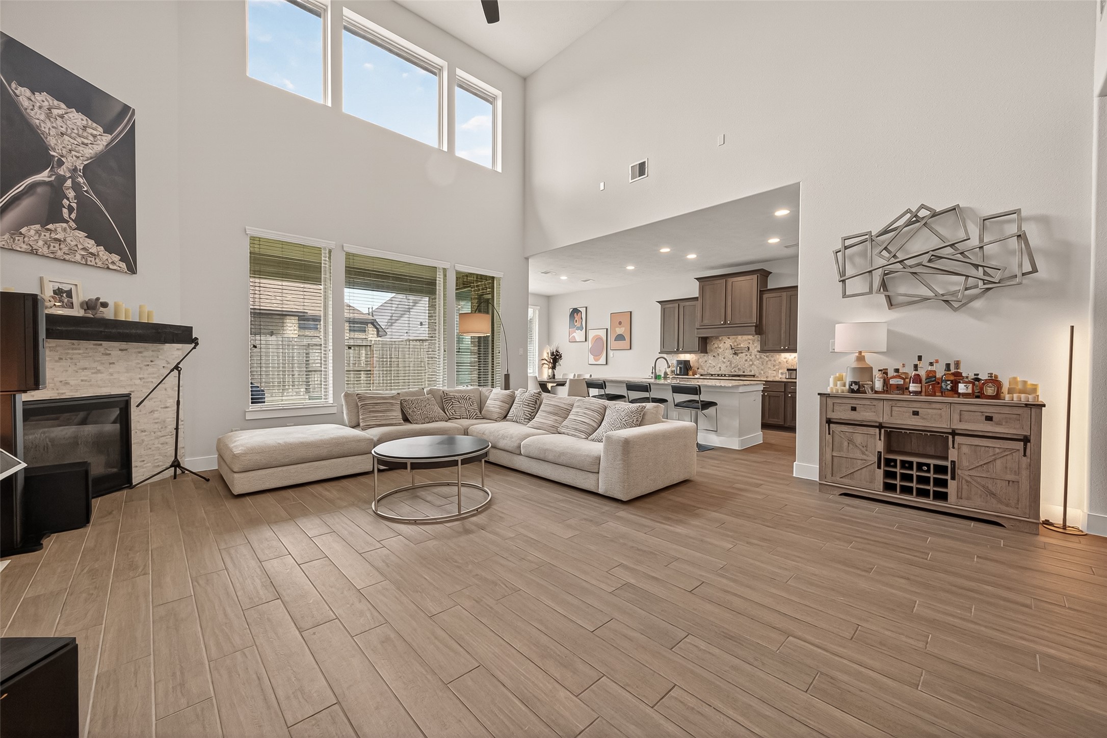1815 Brea Rdg Trail Katy, TX 77494 - Photo 42 of 43 This spacious living area features high ceilings, abundant natural light from large windows, and an open floor plan connecting to a modern kitchen. It includes a cozy fireplace, sleek wood flooring, and contemporary decor, perfect for comfortable living and entertaining.