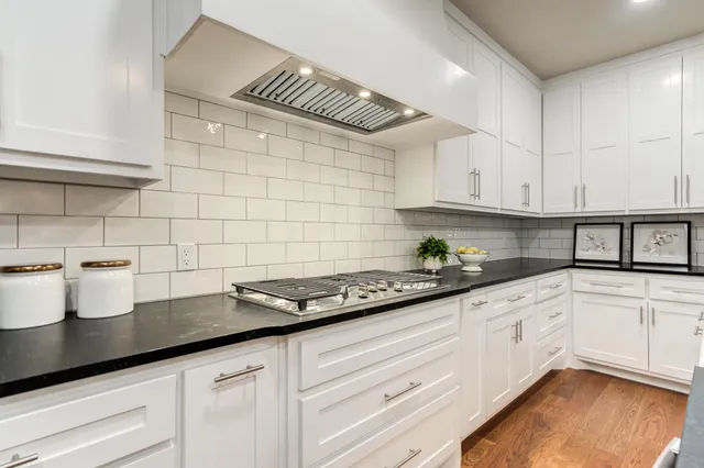 a kitchen with granite countertop a sink a stove and cabinets