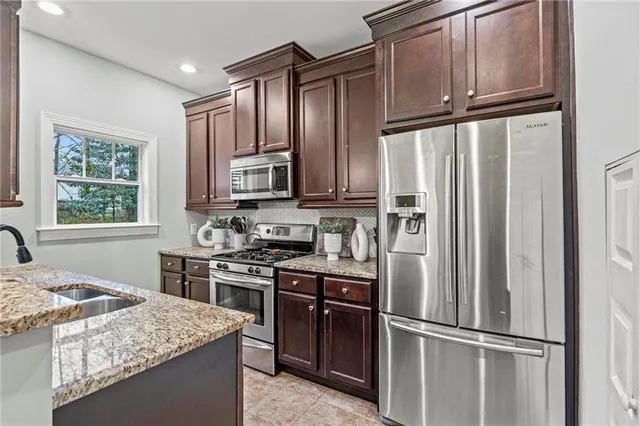 a kitchen with stainless steel appliances granite countertop a refrigerator stove top oven and sink