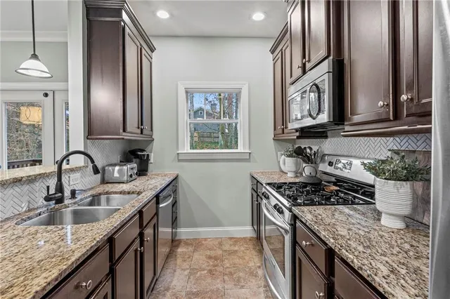 a kitchen with stainless steel appliances granite countertop a sink stove and cabinets