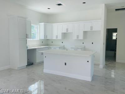 5017 42nd Street Northeast Naples, FL 34120 - Photo 3 of 5 a kitchen with white cabinets appliances a sink