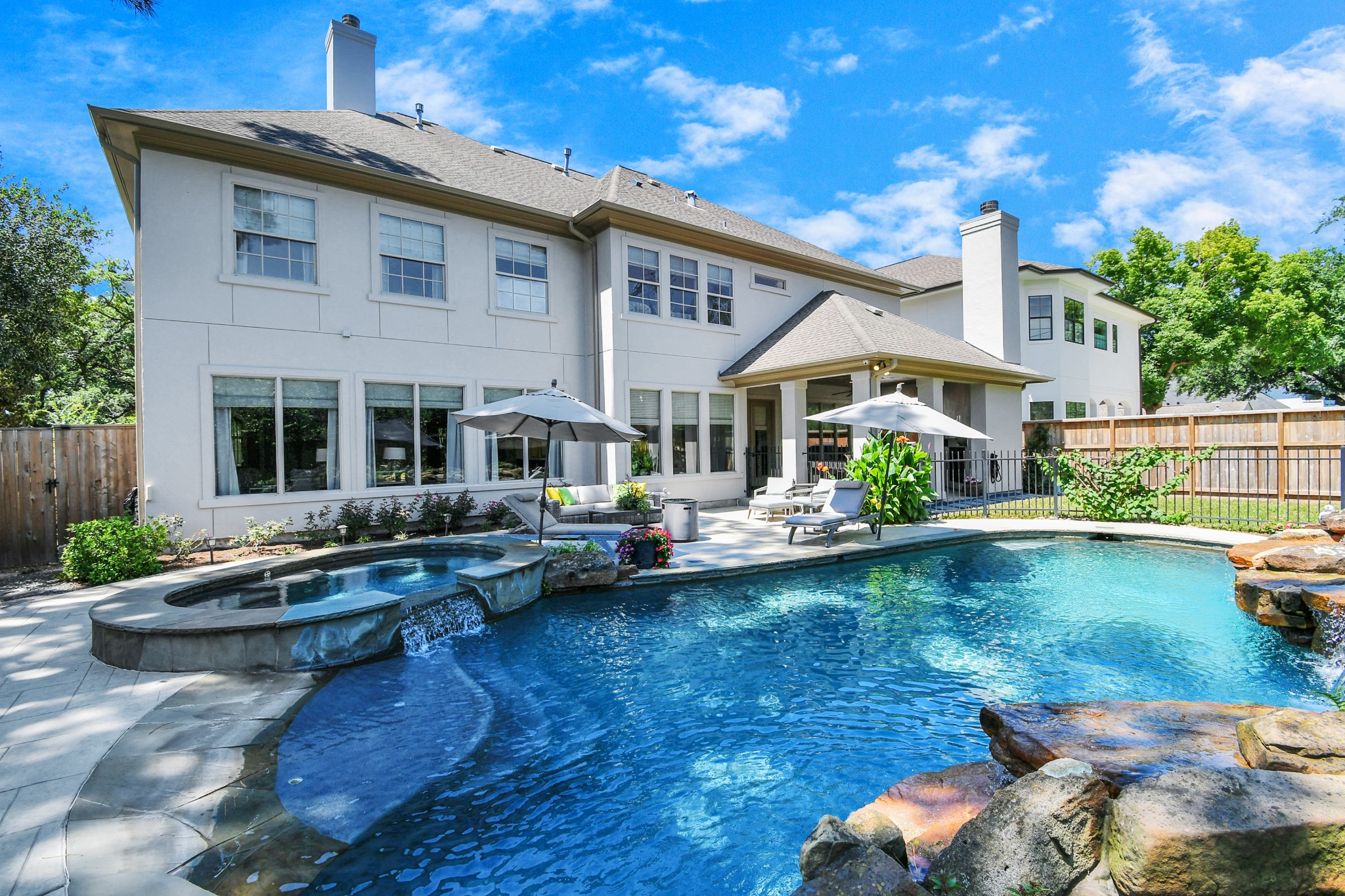 Discover the ultimate backyard oasis with this sparkling pool, featuring a soothing waterfall and lush landscaping. Perfect for relaxation and outdoor enjoyment.