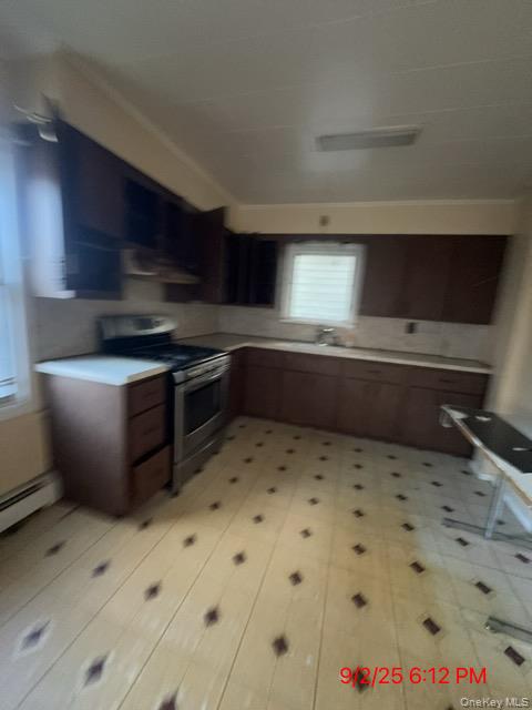 220-18 91st Road Queens, NY 11428 - Photo 4 of 9 Kitchen with electric range, light countertops, a baseboard radiator, and wall chimney exhaust hood