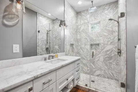 a bathroom with a granite countertop sink a mirror and shower
