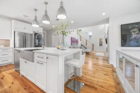 a large white kitchen with a large island oven a stove and white cabinets