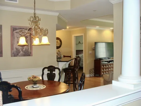 a dining room with wooden floor a chandelier a wooden table and chairs